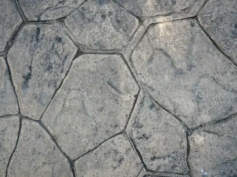 Close-up of gray stamped concrete patterned to resemble irregular hexagonal flagstone pavers